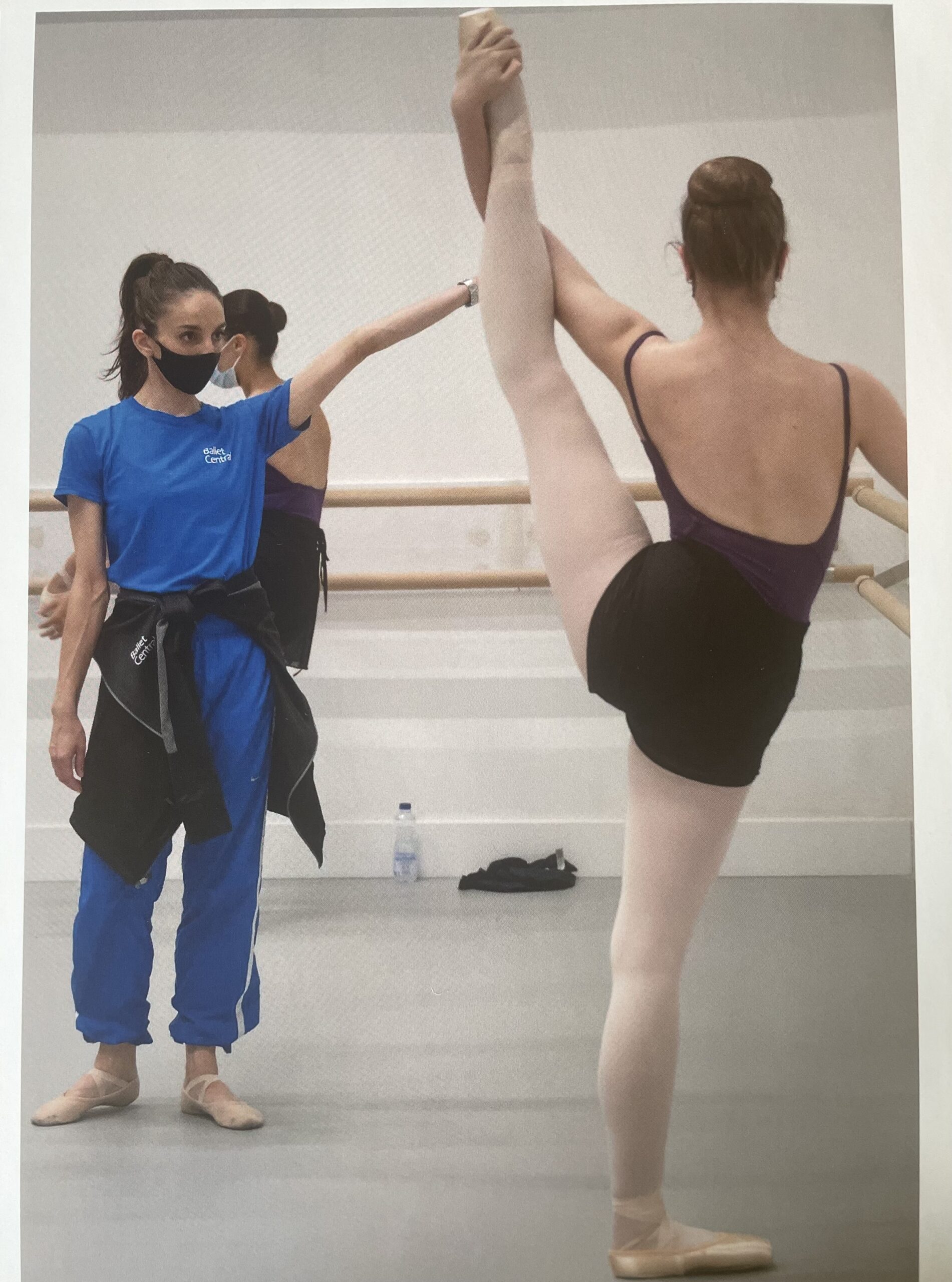 Kate Lyons teaching Ballet Class, correcting dancer's hip placement during stretch / shouldering the leg, at Central School of Ballet